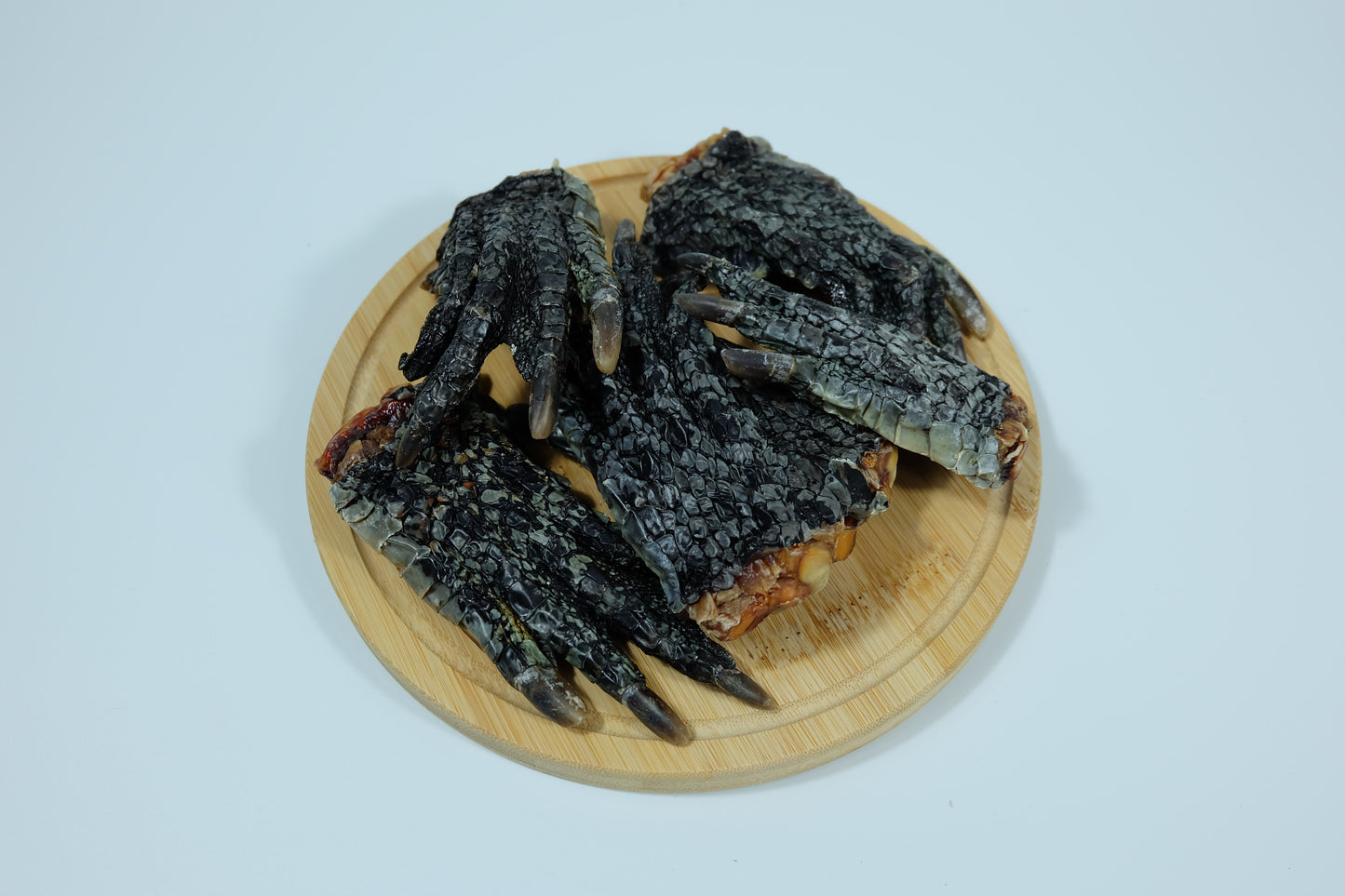 Dehydrated crocodile feet for dogs displayed on a round wooden plate – single-ingredient pet treat